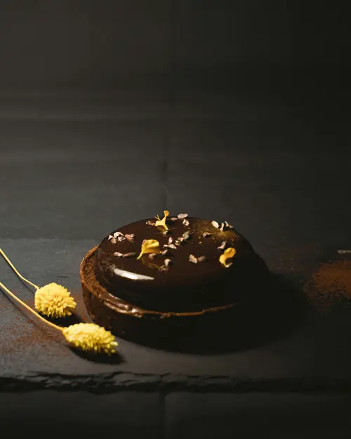 Entremets au chocolat décoré de feuilles d'or sur fond sombre