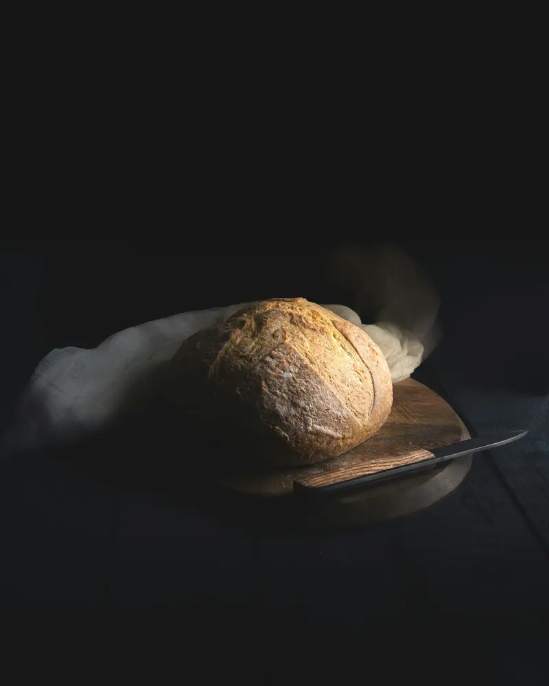 Pain au levain à la croûte dorée sur une planche, dans la pénombre